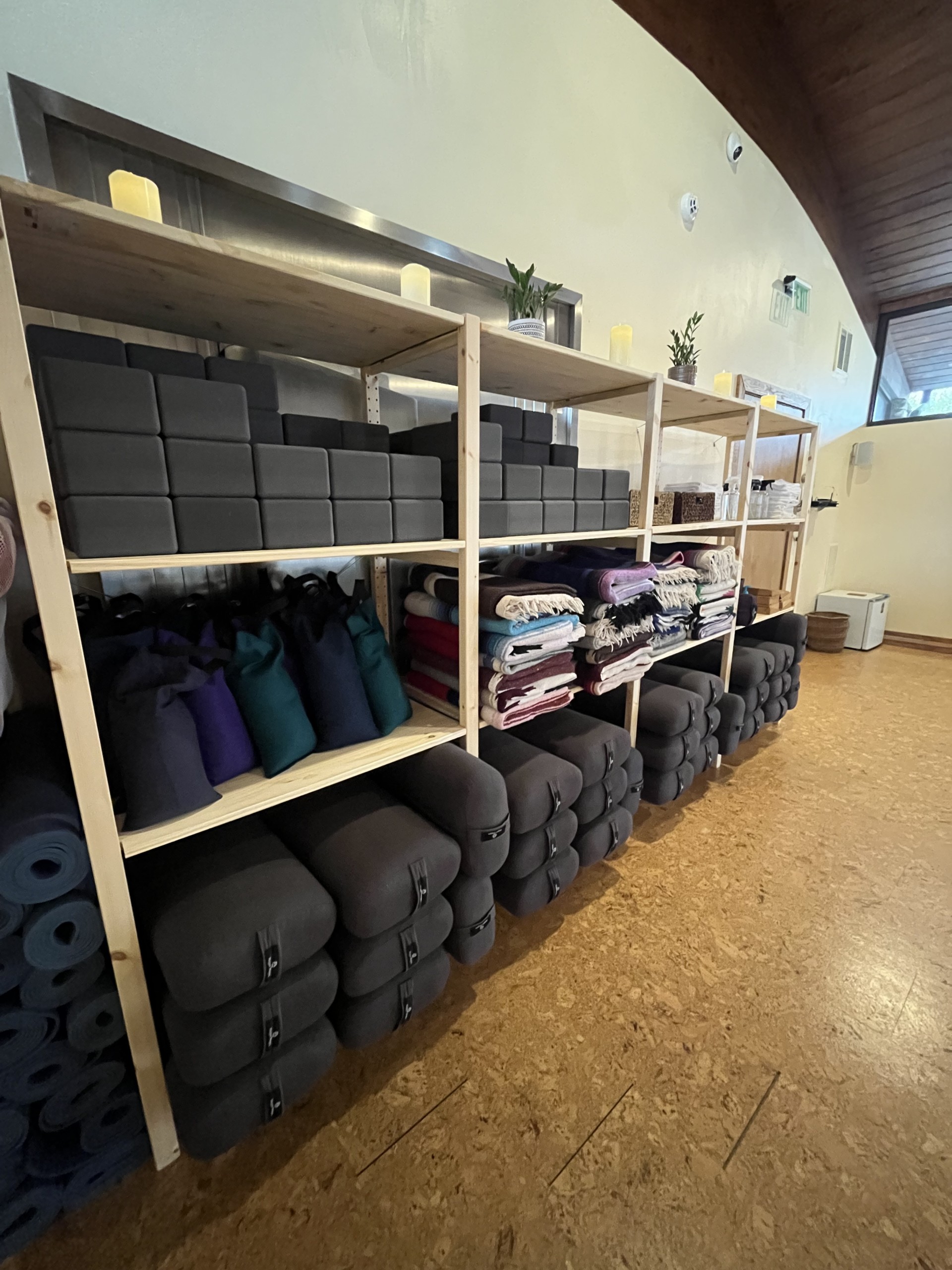Wooden shelves lined with yoga mats and tools.